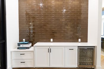 A kitchen with a white cabinet and a brown tiled wall.